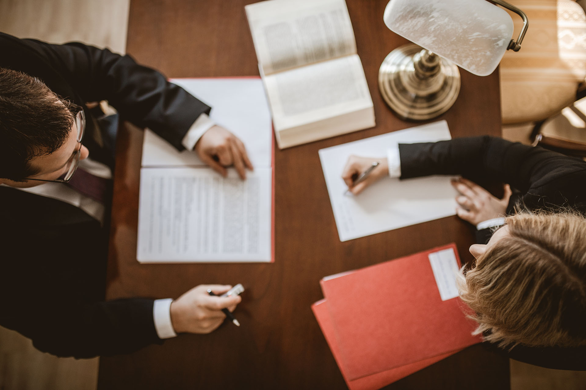 Bild von Oben, 2 Personen sitzen am Tisch, Arbeitssituation